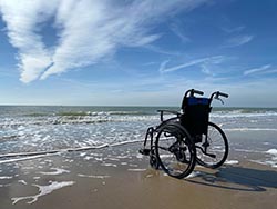 empty wheelchair on warm beach coastline