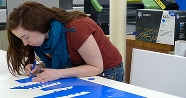 print technology student workin with vinyl on a banner